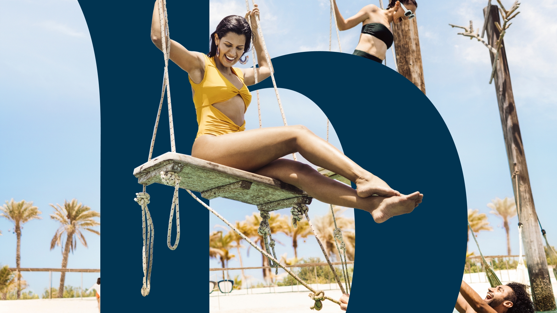 Western women smiling on swing at Al Ain beach
