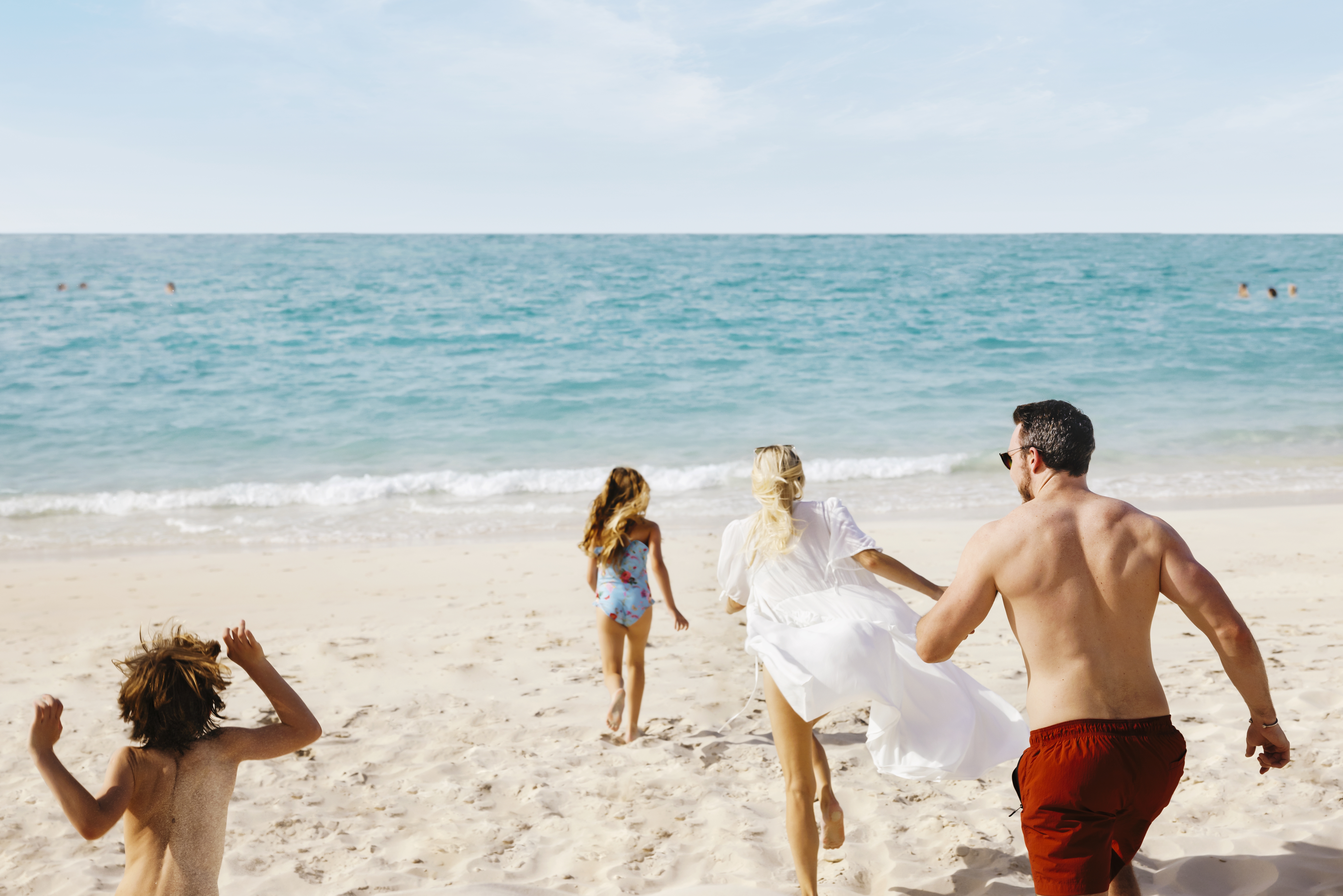 Western family running on Saadiyat Beach towards the water