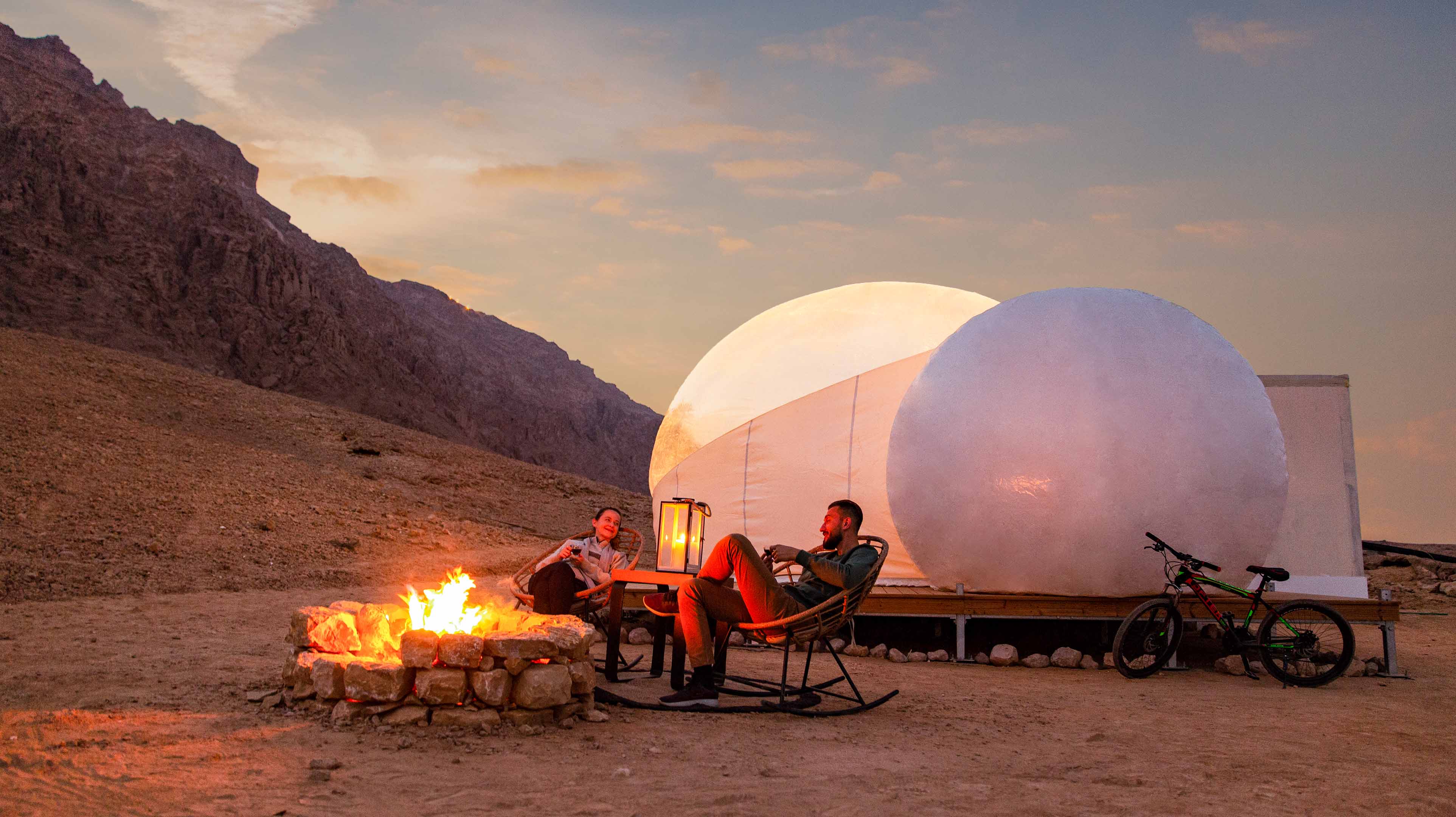 A couple sitting by a campfire at Jebel Hafit
