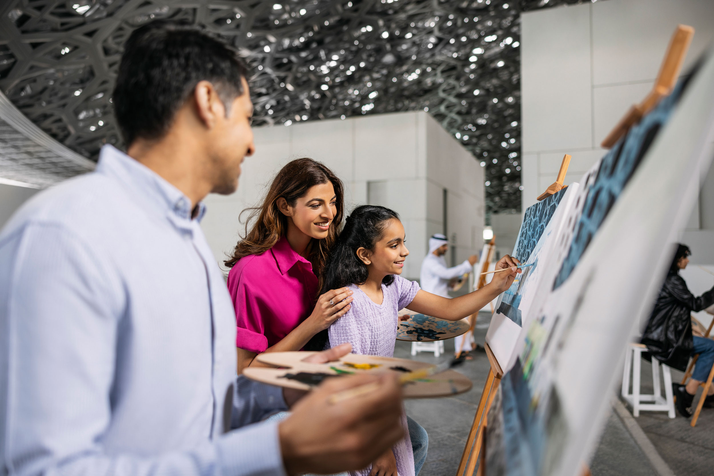 Child painting with parents at Abu Dhabi Louvre