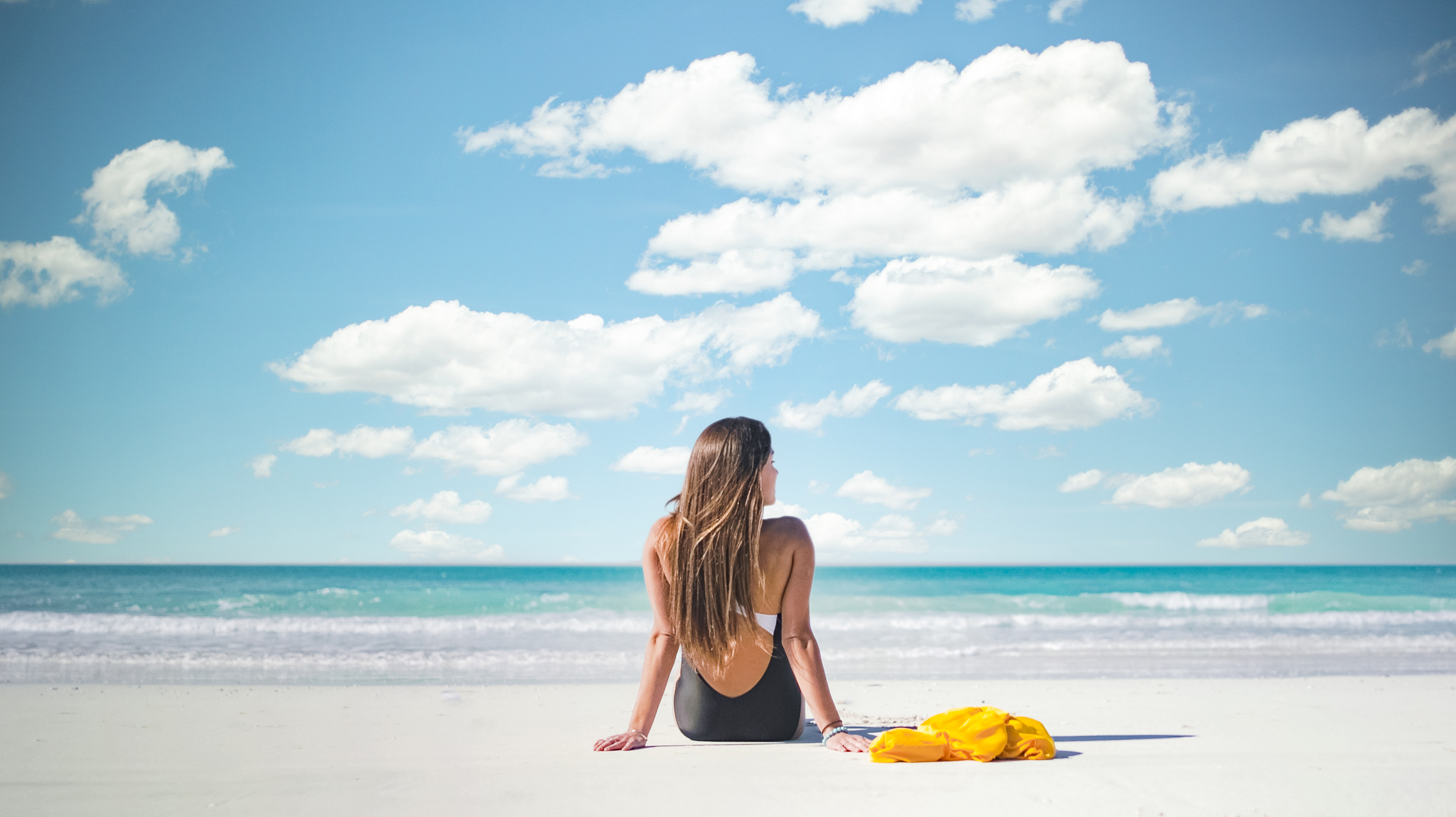 Woman in a black swimsuit sitting on the beach in the Emirate of Abu Dhabi